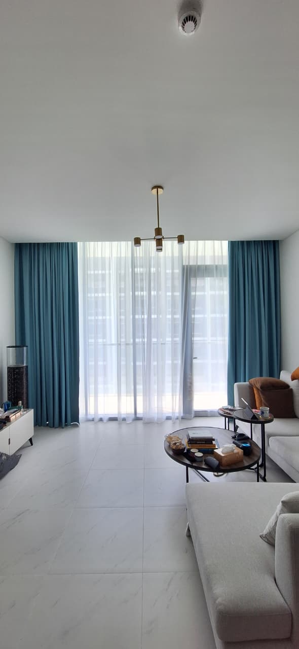 Teal curtains and white sheers in a bright living room